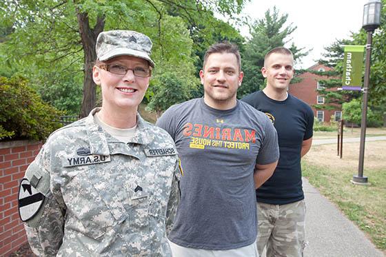 Photo of three military members, one in uniform, pose on Shadyside Campus
